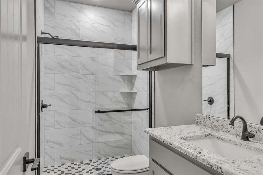 Bathroom with walk in shower, vanity, and toilet