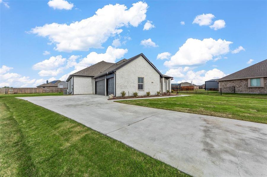 View of side of home with a garage and a lawn