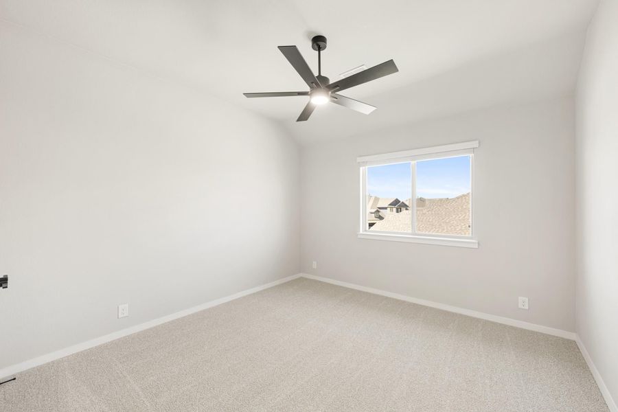 Empty bedroom with carpet flooring, vaulted ceiling, ceiling fan, and single window with neighborhood view