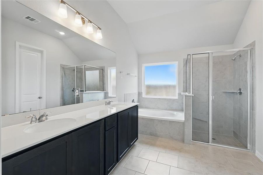 Full bath with lofted ceiling, a garden tub, double vanity, a shower stall, and tile patterned floors