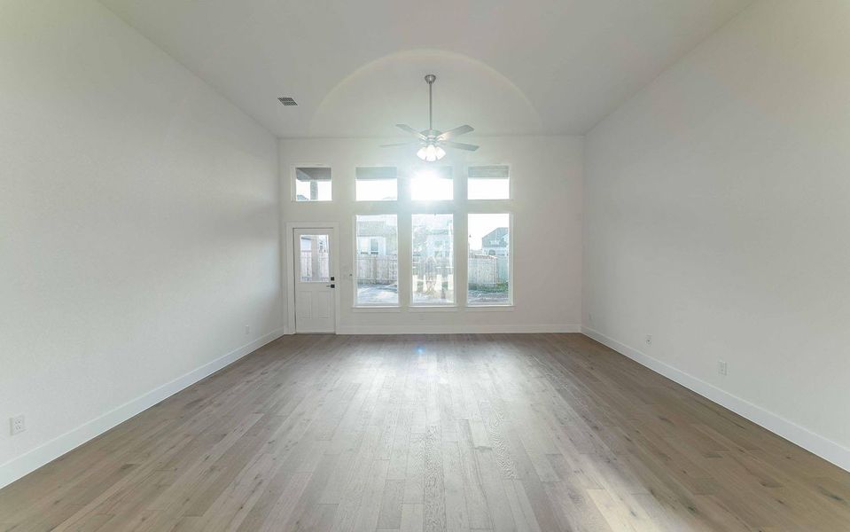 Unfurnished living room featuring a ceiling fan, wood finished floors, and vaulted ceiling