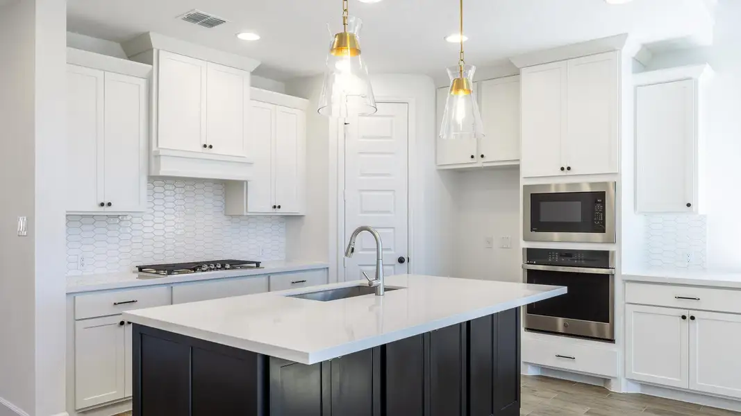 Kitchen with tasteful backsplash, appliances with stainless steel finishes, recessed lighting, an island with sink, and white cabinets