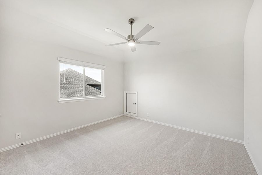 Empty bedroom with white walls, carpet flooring, ceiling fan, and a single window