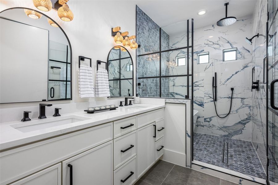 Quartz-topped vanities, refined cabinetry, and statement fixtures make this bathroom a serene sanctuary.