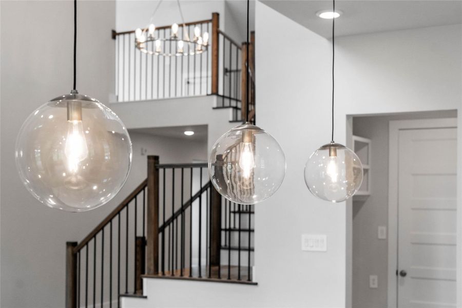 Three exquisite, clear glass pendant lights that elegantly hang above the kitchen island, providing focused task lighting and a touch of refined style.