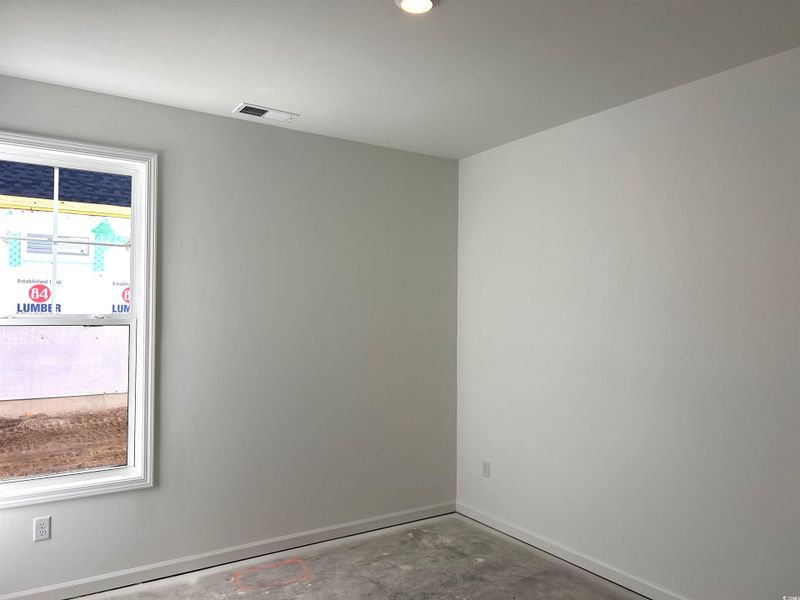 Empty room featuring unfinished concrete floors and baseboards