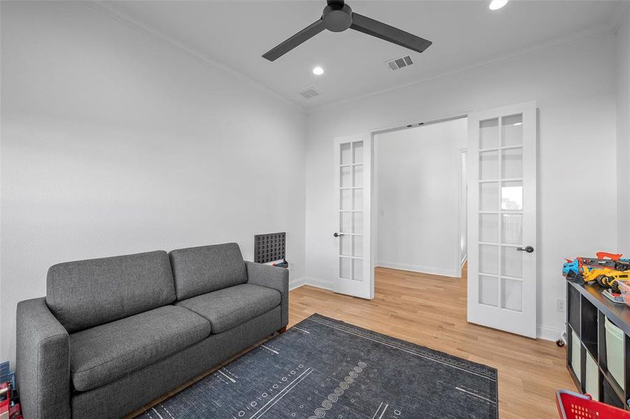 Living room featuring ornamental molding, light wood finished floors, recessed lighting, and french doors Living room featuring ornamental molding, light wood finished floors, recessed lighting, and french doors