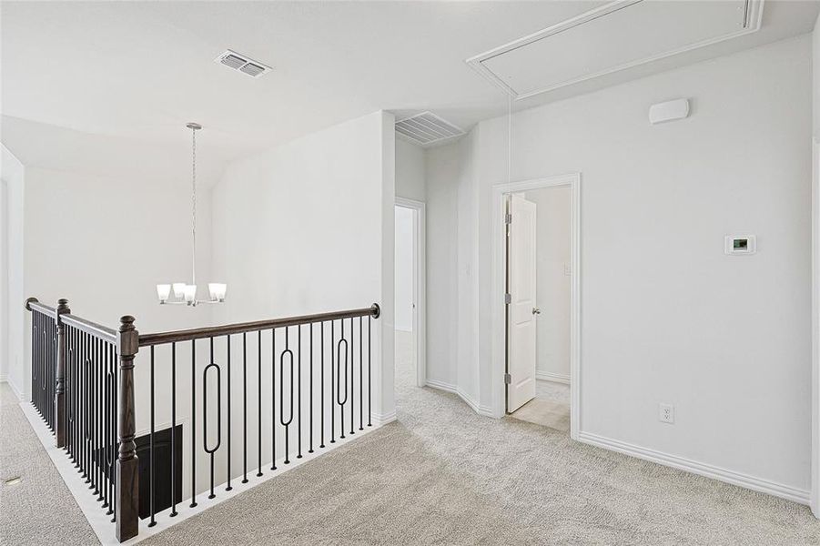 Hallway featuring light carpet and a notable chandelier