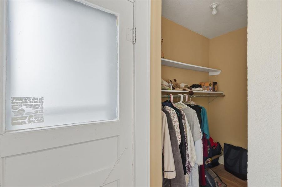 Recessed closet with a single overhead light fixture, two shelving units, and a clothes hanging rod