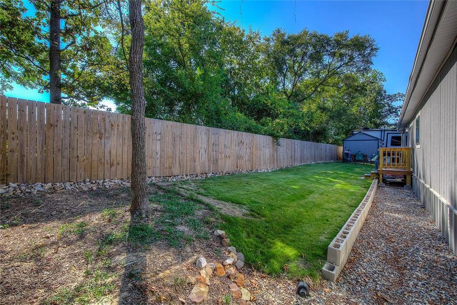 Fenced backyard featuring a storage shed