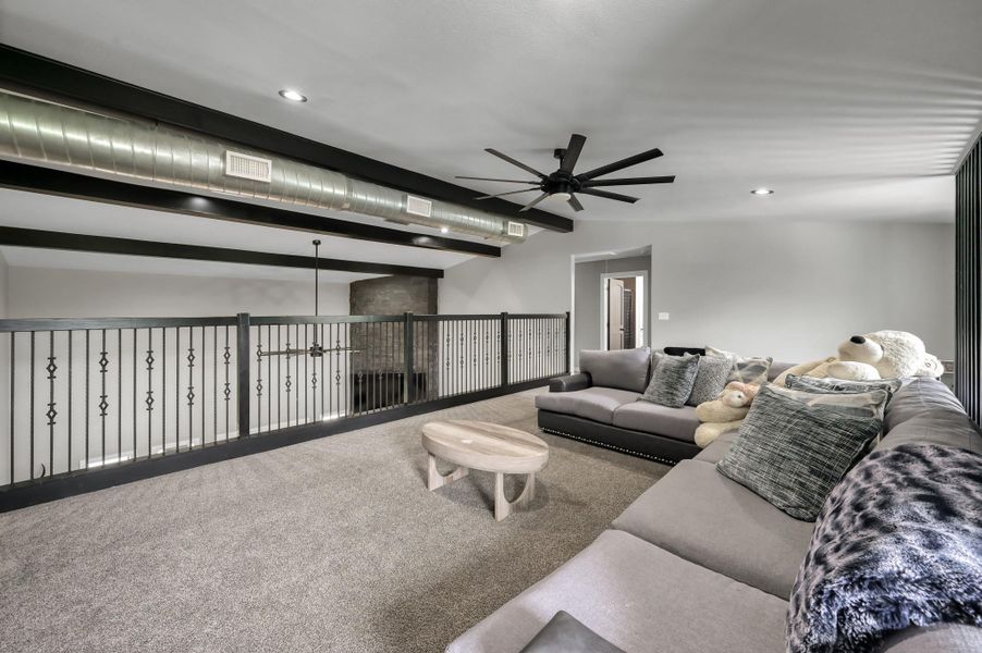 Spacious gameroom features plush carpeting, and modern industrial elements like exposed ductwork and black ceiling beams. Perfect for relaxation or entertaining, it offers a comfortable and stylish atmosphere.