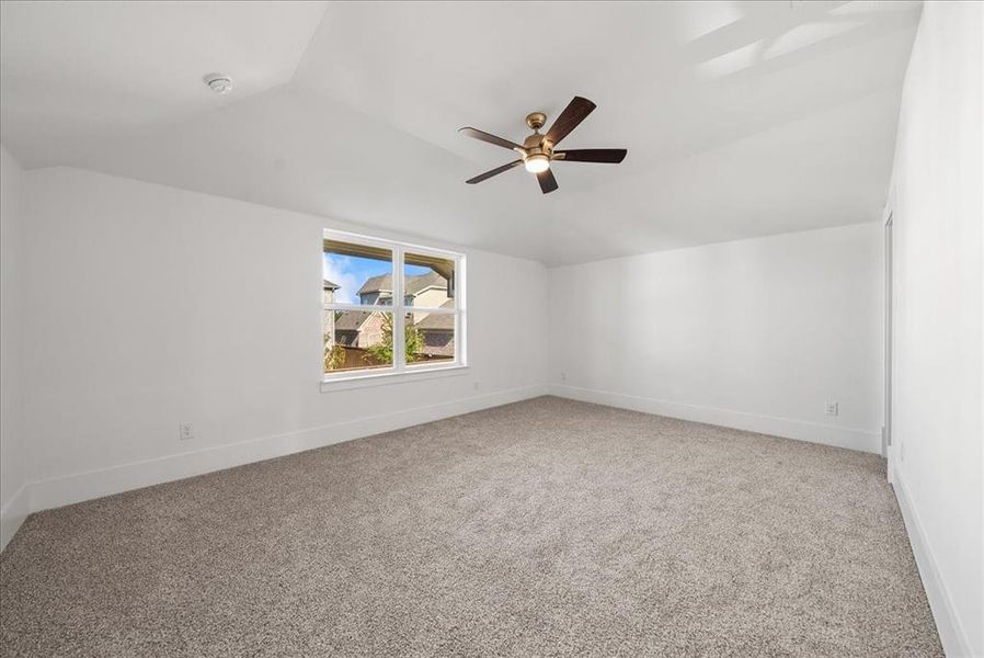 Bedroom featuring vaulted ceiling, light carpet, and a ceiling fan Bedroom featuring vaulted ceiling, light carpet, and a ceiling fan