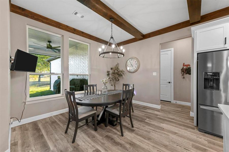 Dining room featuring beam ceiling, light hardwood / wood-style floors, and ceiling fan with notable chandelier