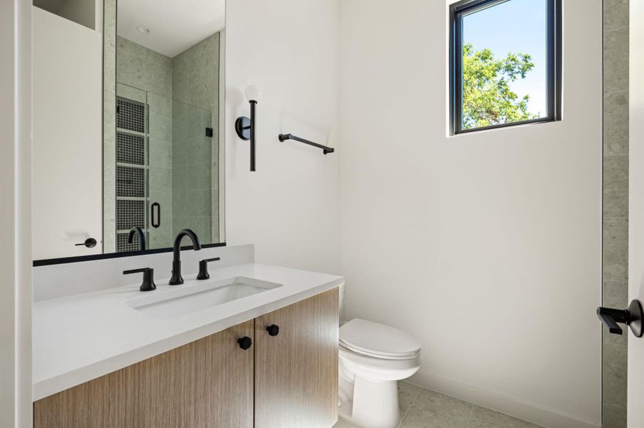 Clean lines and stone counters define this modern bathroom with high ceilings.