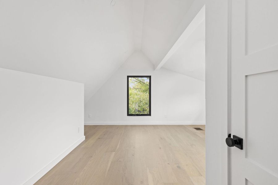 Additional living space featuring lofted ceiling and light wood-style flooring