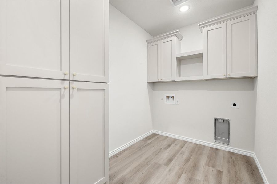 Functional laundry space featuring ample storage with built-in cabinetry and durable flooring. Functional laundry space featuring ample storage with built-in cabinetry and durable flooring.