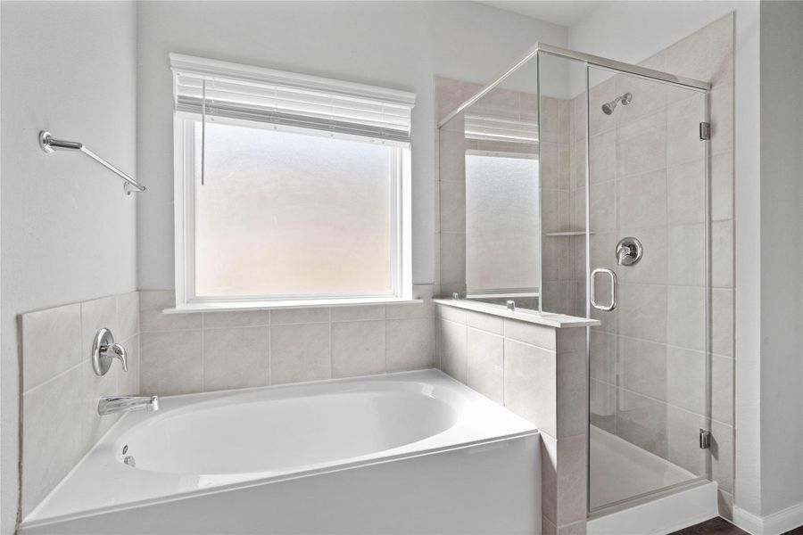Additional view of the primary bathroom showcases the soaking tub and walk-in shower with window allowing in natural lighting.