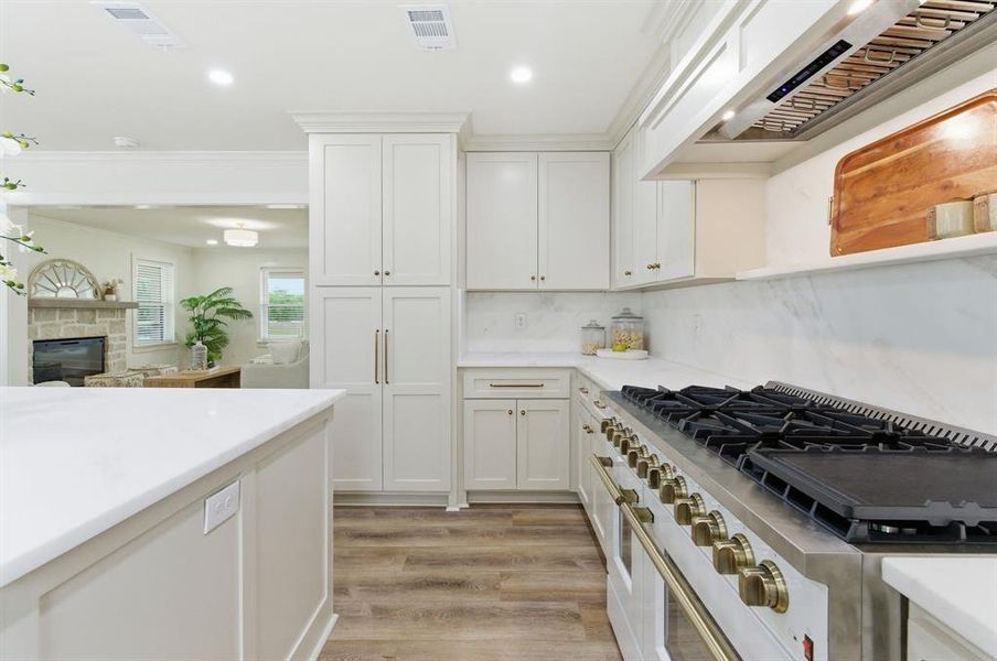 The kitchen features extensive white cabinetry, light-colored countertops, and hardwood flooring The kitchen features extensive white cabinetry, light-colored countertops, and hardwood flooring