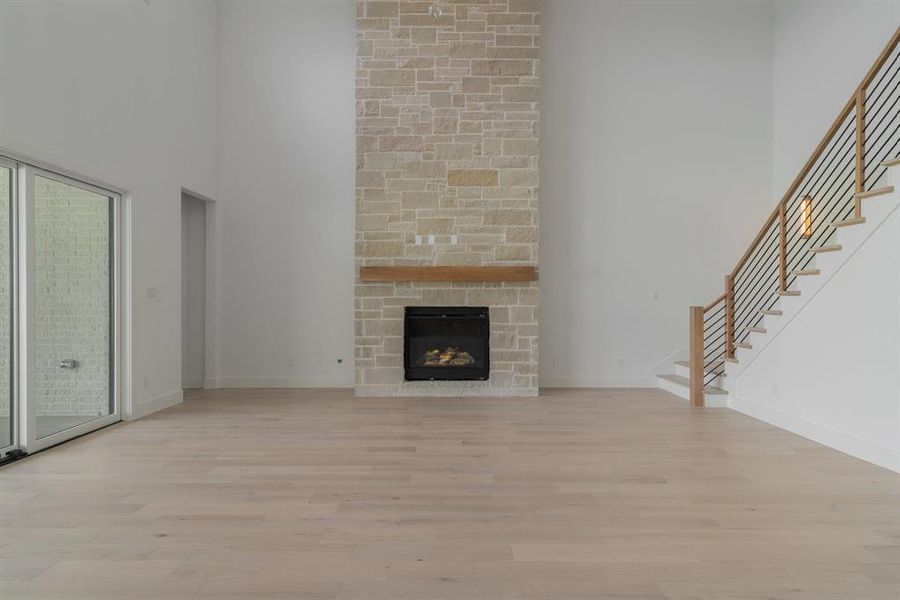 Unfurnished living room featuring a stone fireplace, brick wall, and light hardwood / wood-style floors