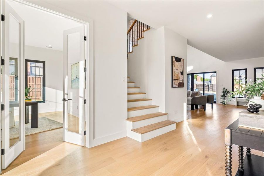 Stairway featuring wood finished floors, vaulted ceiling, and recessed lighting Stairway featuring wood finished floors, vaulted ceiling, and recessed lighting