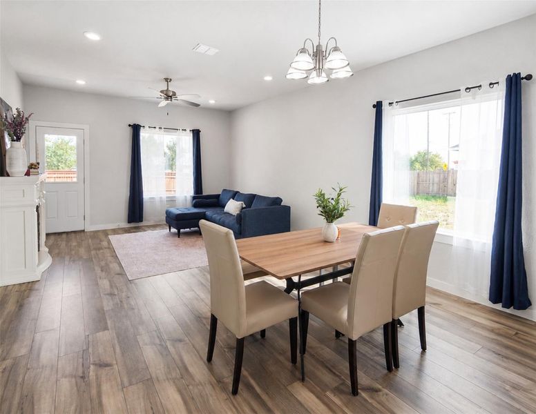 Gleaming wood-look floors anchor this airy, open-concept dining space framed by large windows. Gleaming wood-look floors anchor this airy, open-concept dining space framed by large windows.