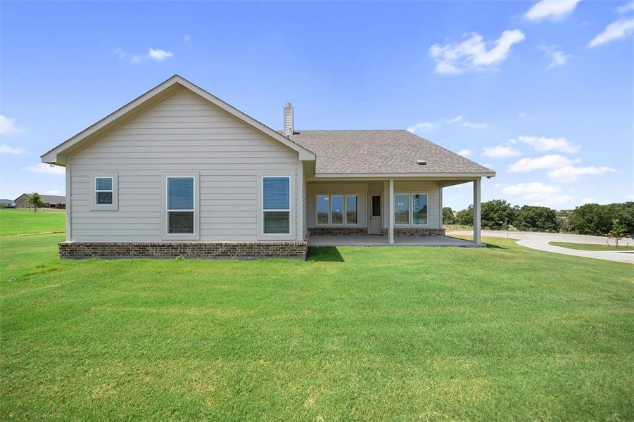 Rear view of house featuring a patio, a shingled roof, and a lawn Rear view of house featuring a patio, a shingled roof, and a lawn