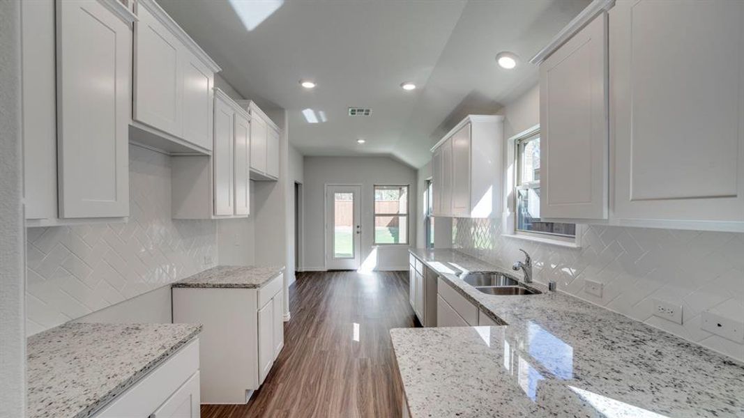 Kitchen with light stone countertops, white cabinets, dark wood-style flooring, recessed lighting, and tasteful backsplash