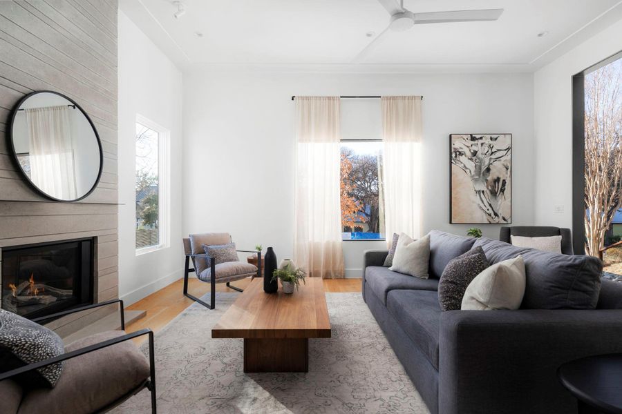 Living room with a ceiling fan, wood finished floors, and a fireplace