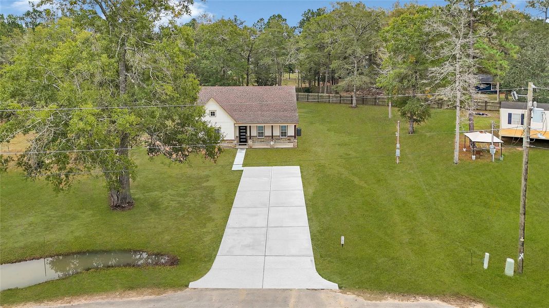 This photo shows a charming, single-story home with a spacious front yard and a long driveway. The property is surrounded by mature trees, providing a serene and private atmosphere. A small pond is visible on the left, adding to the scenic beauty. Ideal for those seeking a peaceful retreat. This photo shows a charming, single-story home with a spacious front yard and a long driveway. The property is surrounded by mature trees, providing a serene and private atmosphere. A small pond is visible on the left, adding to the scenic beauty. Ideal for those seeking a peaceful retreat.