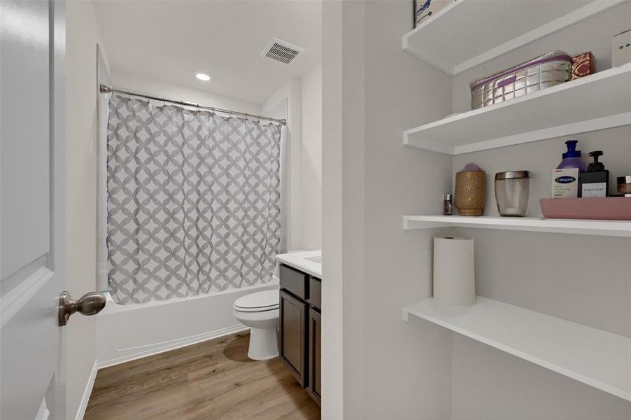 Bathroom featuring visible vents, wood finished floors, toilet, vanity, and shower / tub combo