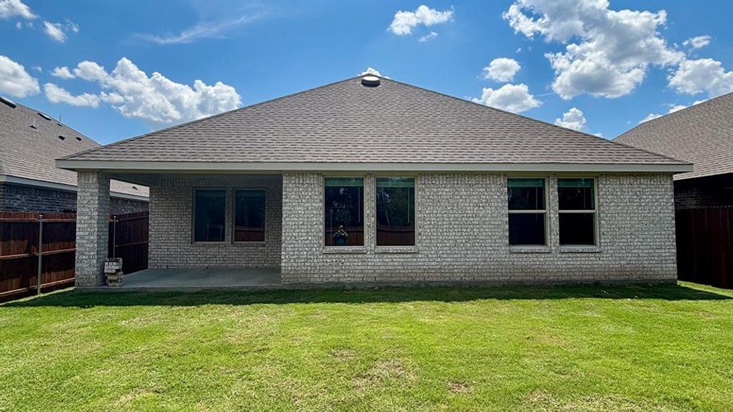 Rear exterior featuring a covered patio, light-colored brick facade, multiple windows, and a shingle roof Rear exterior featuring a covered patio, light-colored brick facade, multiple windows, and a shingle roof