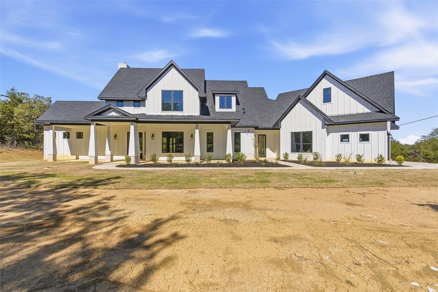 Modern inspired farmhouse featuring covered porch, roof with shingles, and board and batten siding Modern inspired farmhouse featuring covered porch, roof with shingles, and board and batten siding