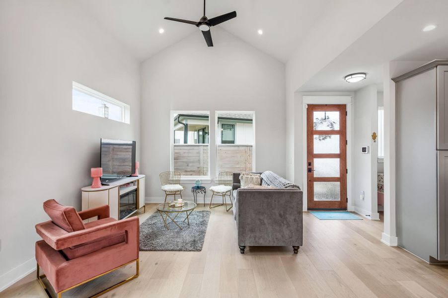 Living area featuring a ceiling fan, light wood finished floors, vaulted ceiling, and recessed lighting
