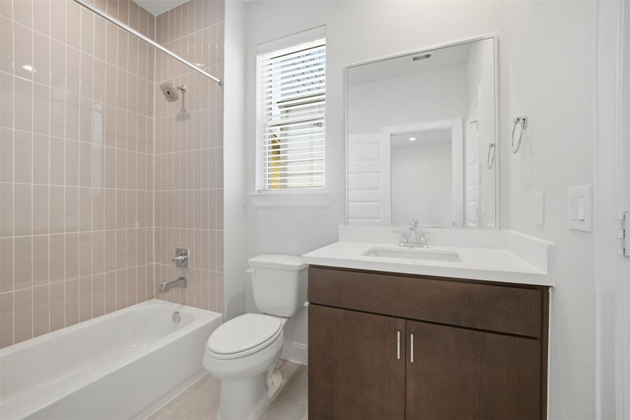 The second bathroom boasts sleek modern fixtures, a chic tiled shower, and abundant natural light for a refreshing and stylish space.