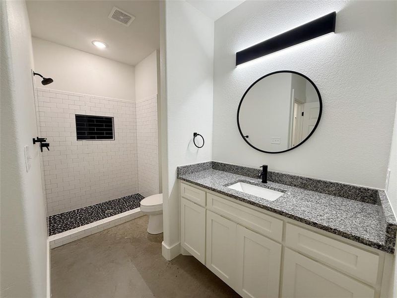 Full bathroom featuring a tile shower and vanity