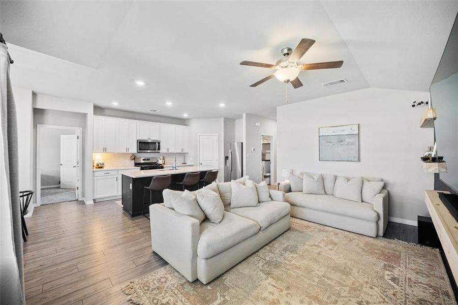 Living area featuring light wood-type flooring, a ceiling fan, recessed lighting, and vaulted ceiling