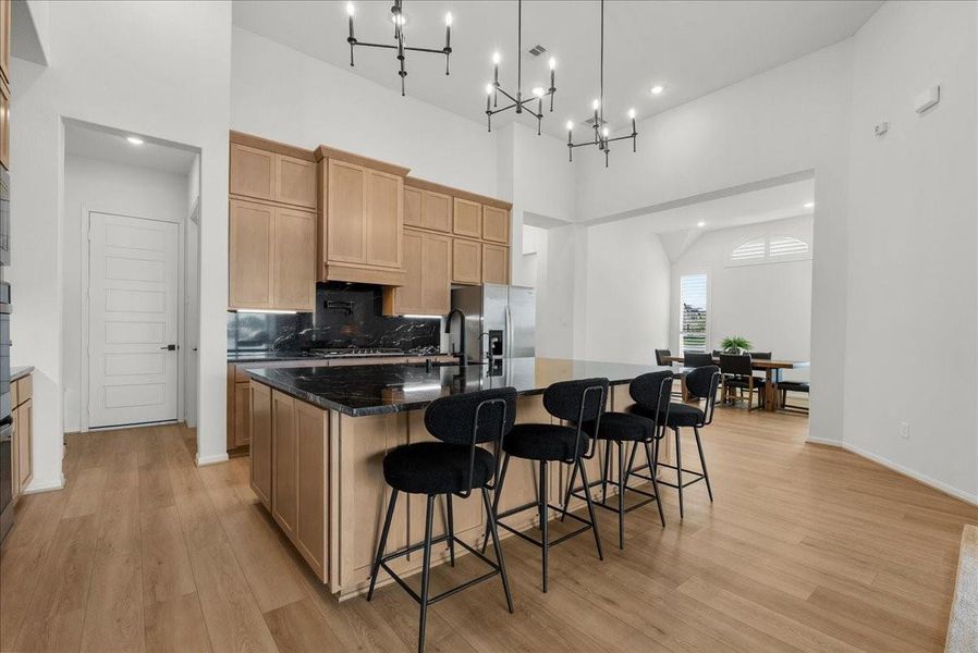 Chef’s kitchen overlooks the spacious living area and boasts double ovens, pot filler, granite countertops, designer backsplash, upgraded cabinetry, stainless steel appliances, stylish finishes, and oversized island seating.