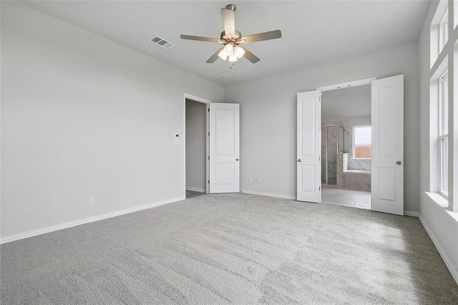 Unfurnished bedroom featuring carpet flooring, baseboards, ensuite bathroom, and a ceiling fan