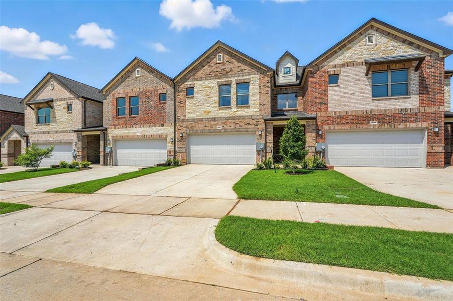 View of front facade with driveway, brick siding, and an attached garage