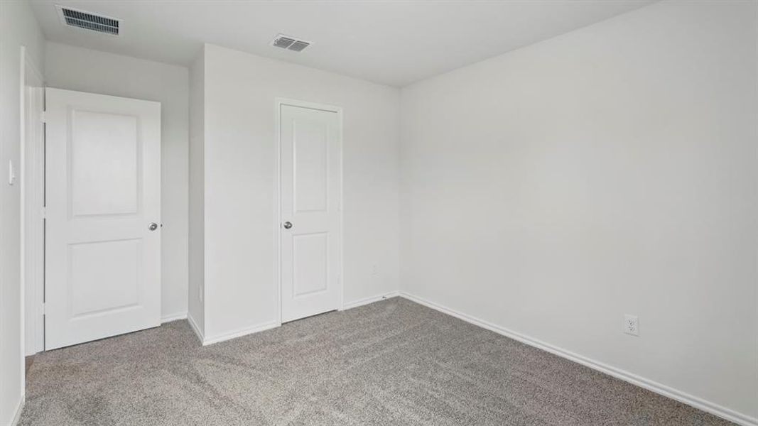 Neutral white wall finishes, two white two-panel interior doors, gray carpet flooring, and white baseboards