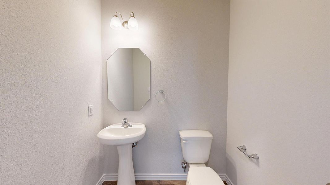 Bathroom featuring a pedestal sink, an octagonal mirror, a toilet, and light-colored walls