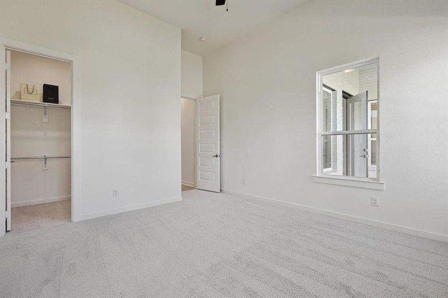 Unfurnished bedroom featuring light carpet, a closet, and a walk in closet