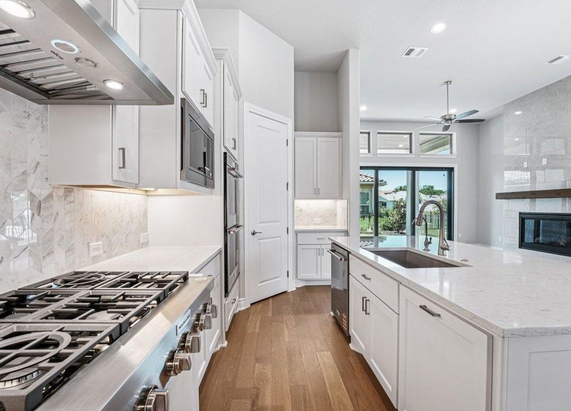 Kitchen featuring appliances with stainless steel finishes, extractor fan, a ceiling fan, wood finished floors, and recessed lighting