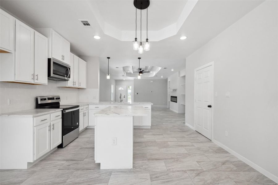 Kitchen with a raised ceiling, stainless steel appliances, a peninsula, a sink, and recessed lighting Kitchen with a raised ceiling, stainless steel appliances, a peninsula, a sink, and recessed lighting