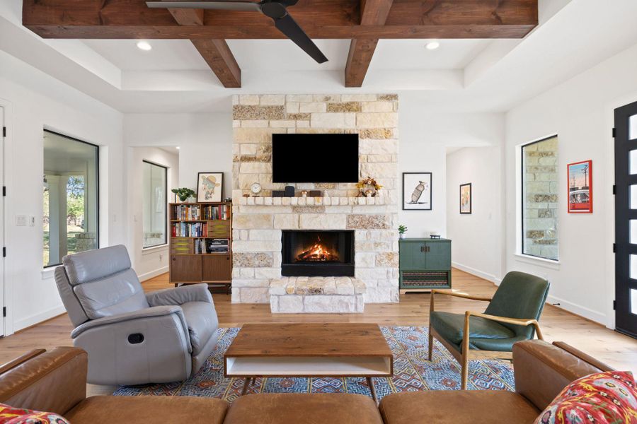 Living area featuring wood finished floors, beamed ceiling, a fireplace, and coffered ceiling