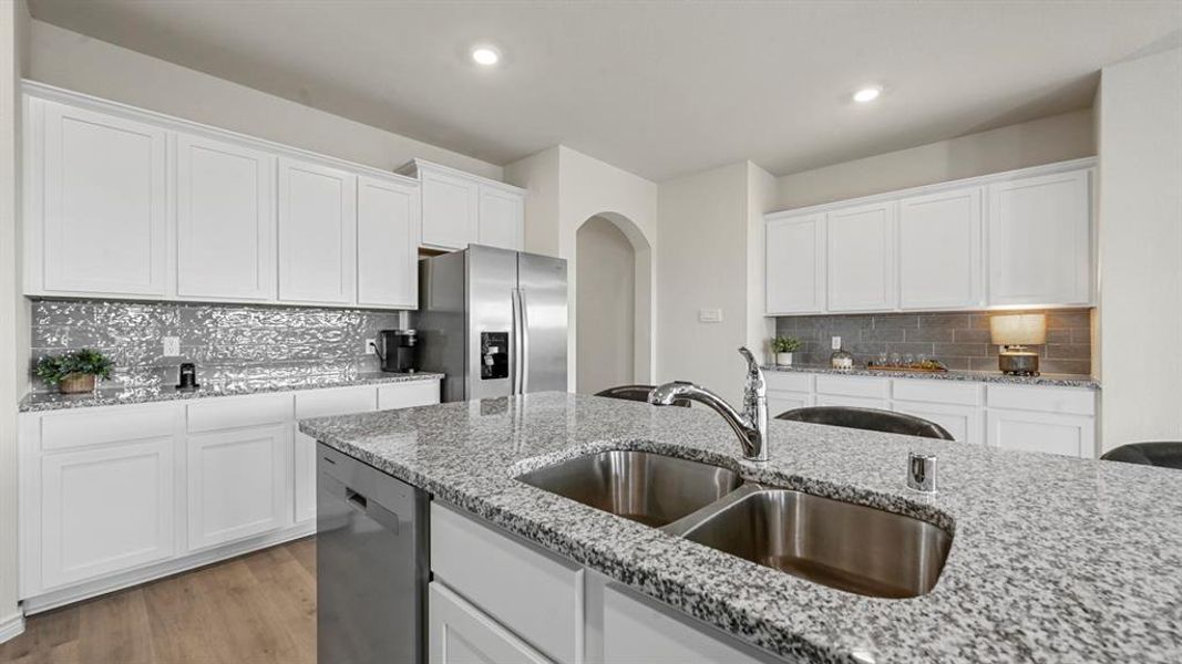 Kitchen featuring decorative backsplash, white cabinetry, arched walkways, appliances with stainless steel finishes, and recessed lighting
