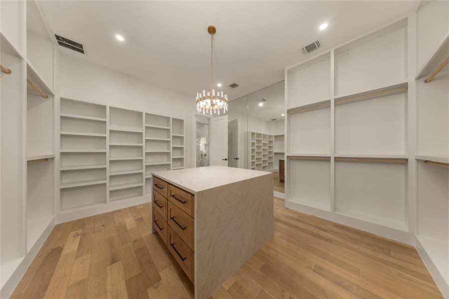 Walk in closet featuring light wood finished floors and suspended lighting