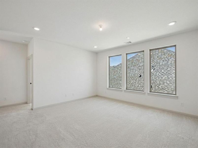Spacious room featuring light-colored carpet flooring, white walls, and recessed ceiling lighting
