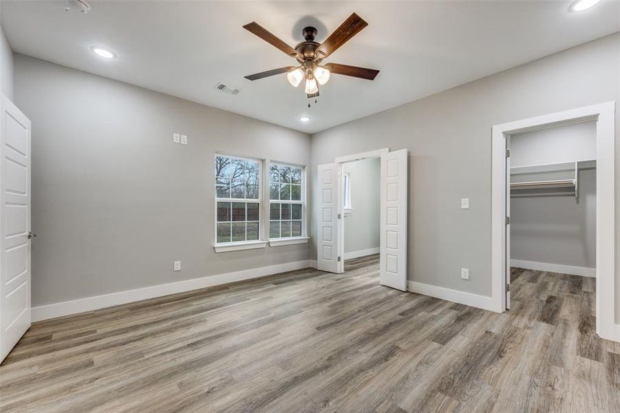 Unfurnished bedroom featuring a walk in closet, recessed lighting, light wood-style floors, and a ceiling fan