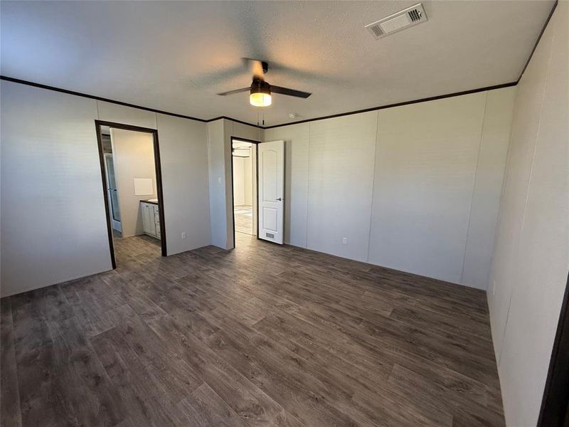 Unfurnished bedroom featuring crown molding, dark wood-style flooring, ceiling fan, a textured ceiling, and connected bathroom